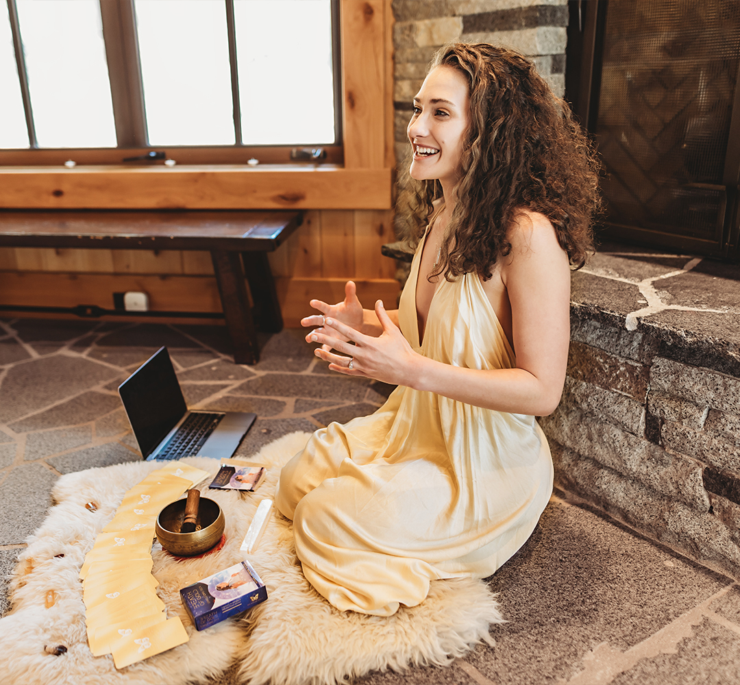 Adrienne Rivera seated on a sheepskin beside a laptop, leading an online breathwork session